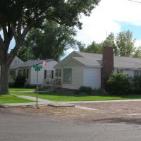 Small white house, yard, and trees.
